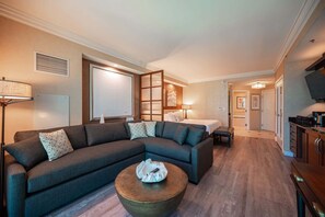 A modern living room with a sectional sofa, a round coffee table, and a bed in the background. - No Resort Fee Strip View Suite+ Free Valet + Pool (Las Vegas)