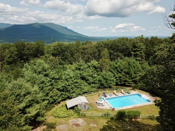Relax by the serene pool surrounded by lush greenery and majestic mountains.