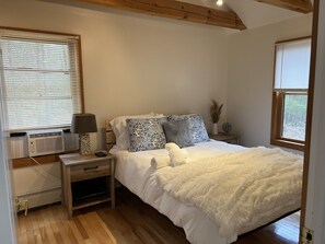 Enjoy a restful stay in this cozy room with a neatly made bed, bedside table, and window with blinds.