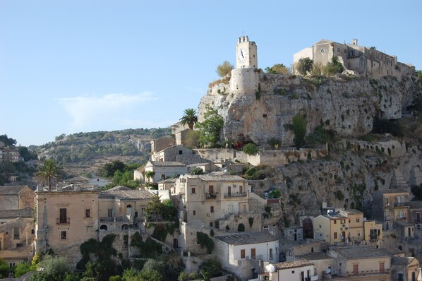 A historic town with a prominent castle on a hill, surrounded by traditional buildings and lush greenery.