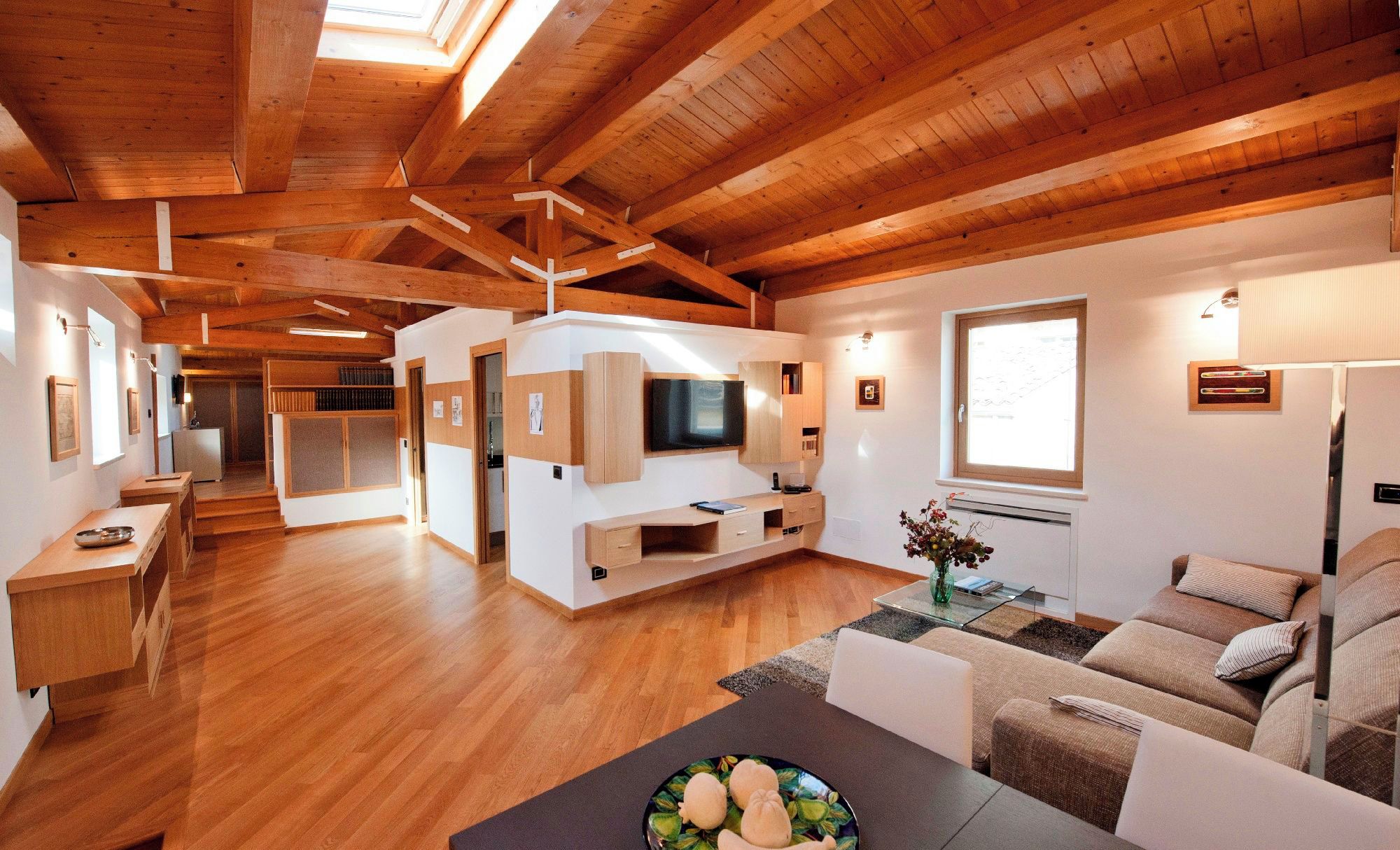 A spacious living area with wooden beams, a TV, and a sofa.