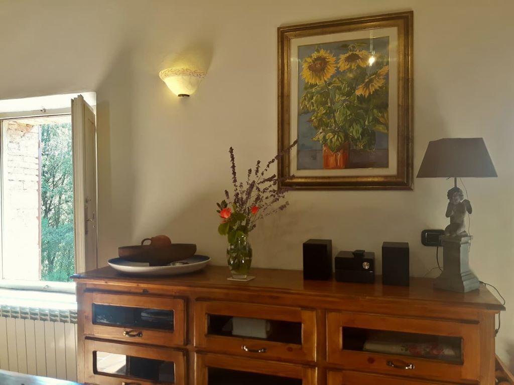 Une commode en bois avec des tiroirs, un tableau encadré représentant des tournesols, un vase avec des fleurs, une statue et une lampe.
