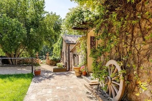 A stone pathway leading to a rustic building with a wheelbarrow and potted plants. - True Tuscany Siena! EntireProperty in exclusive 20P Fenced Pool A/C HotTub WiFi (Sovicille Simignano)