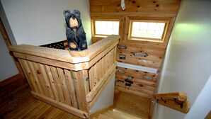 Ein Holzhütten-Interieur mit Schlafkoje, kleinem Fenster und Holzleiter.
