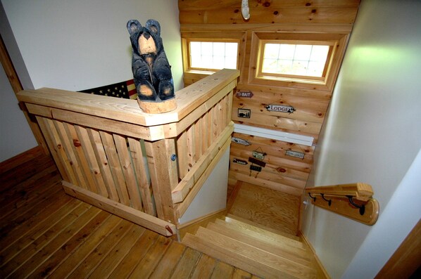 Ein Holzhütten-Interieur mit Schlafkoje, kleinem Fenster und Holzleiter.