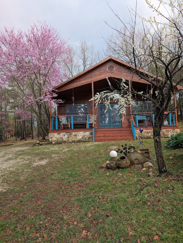 A rustic cabin with a wooden exterior, a porch with blue accents, and a stone foundation.