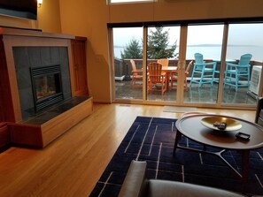 Relax in a spacious living area with a fireplace and sliding glass door leading to a furnished outdoor deck.