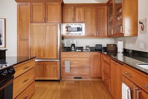 A kitchen with wooden cabinets, a stainless steel refrigerator, a microwave, a coffee maker, and a sink.