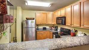 Una cocina con armarios de madera, encimeras de granito y electrodomésticos de acero inoxidable, incluyendo un microondas.