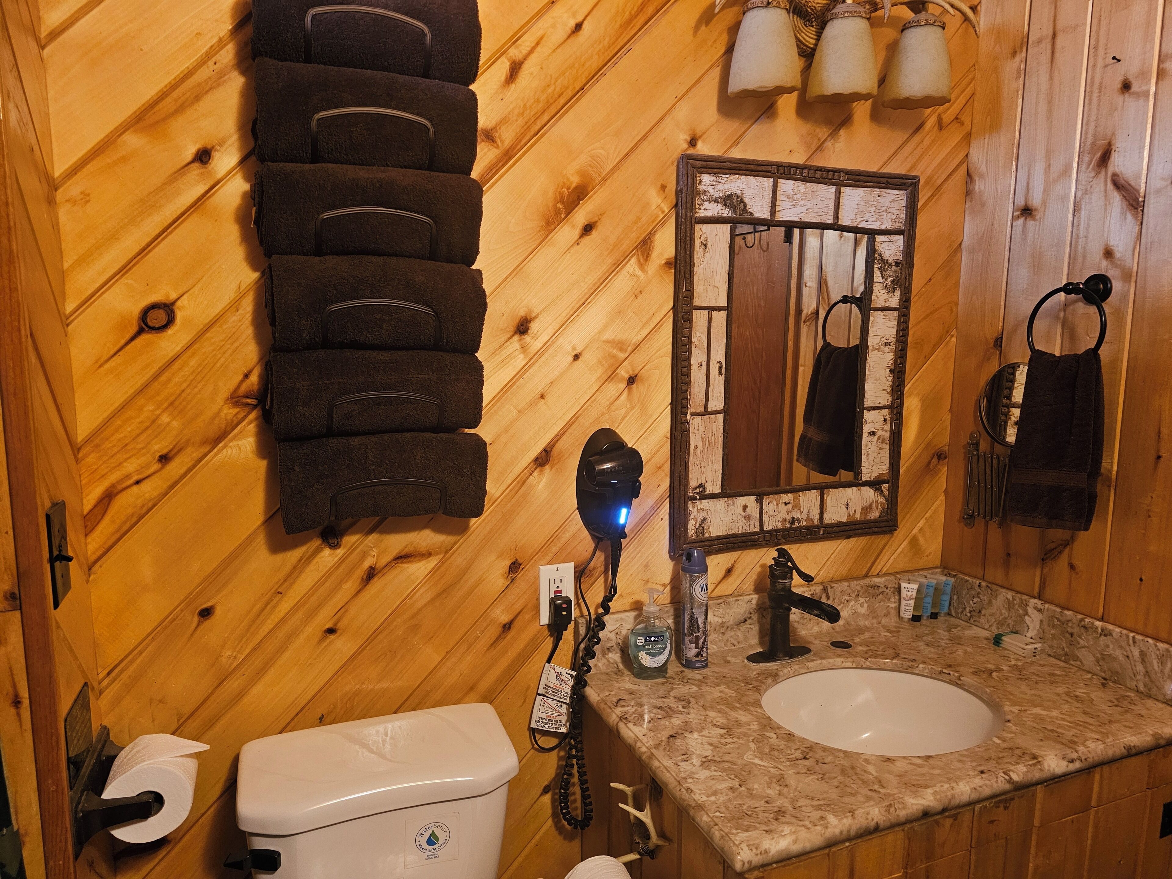 A wooden cabin bathroom with a toilet, sink, and towel rack.