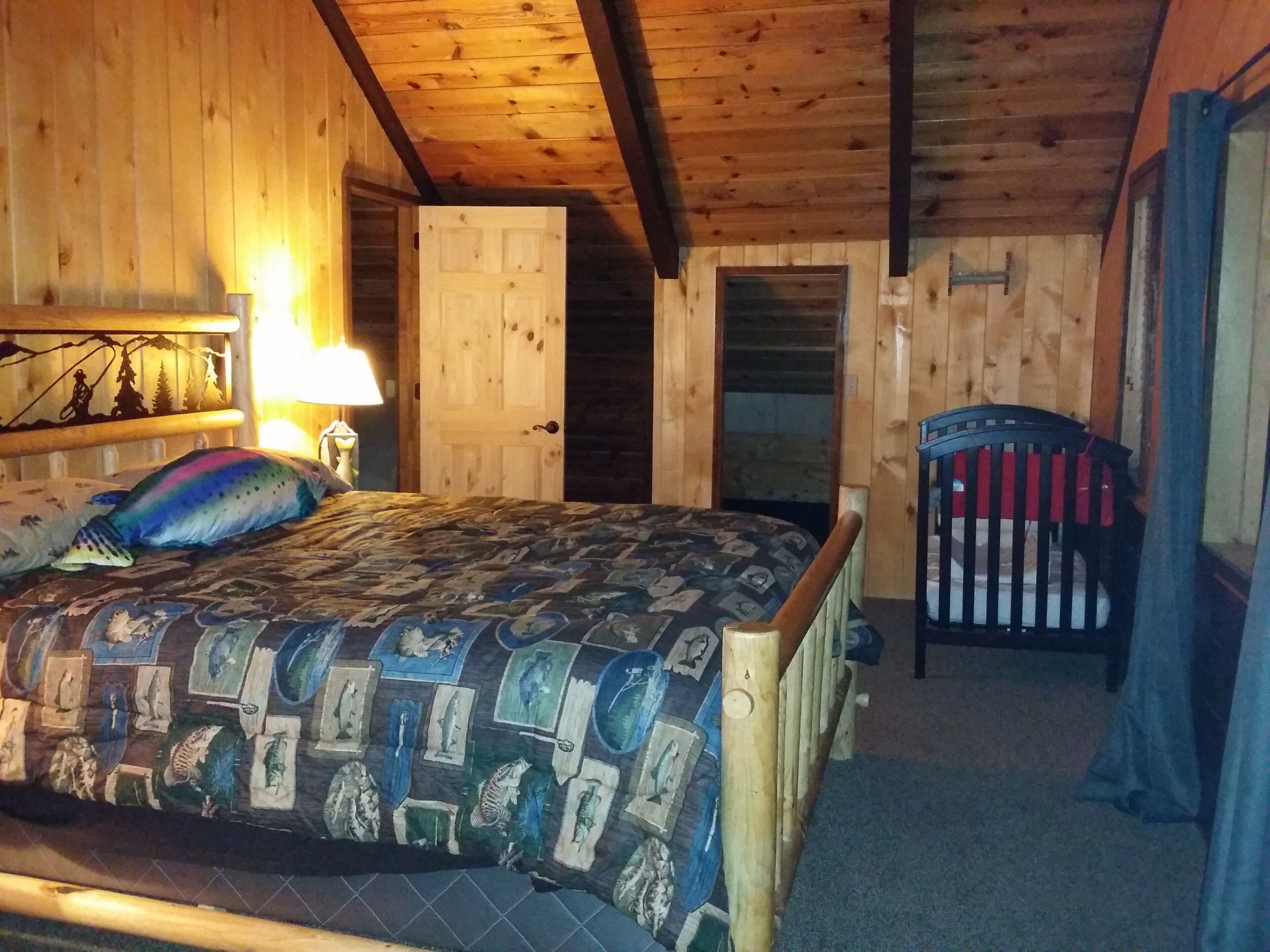 A cozy cabin room with a bed, a chair, and a wooden ceiling.