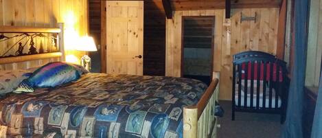 A cozy cabin room with a bed, a chair, and a wooden ceiling.