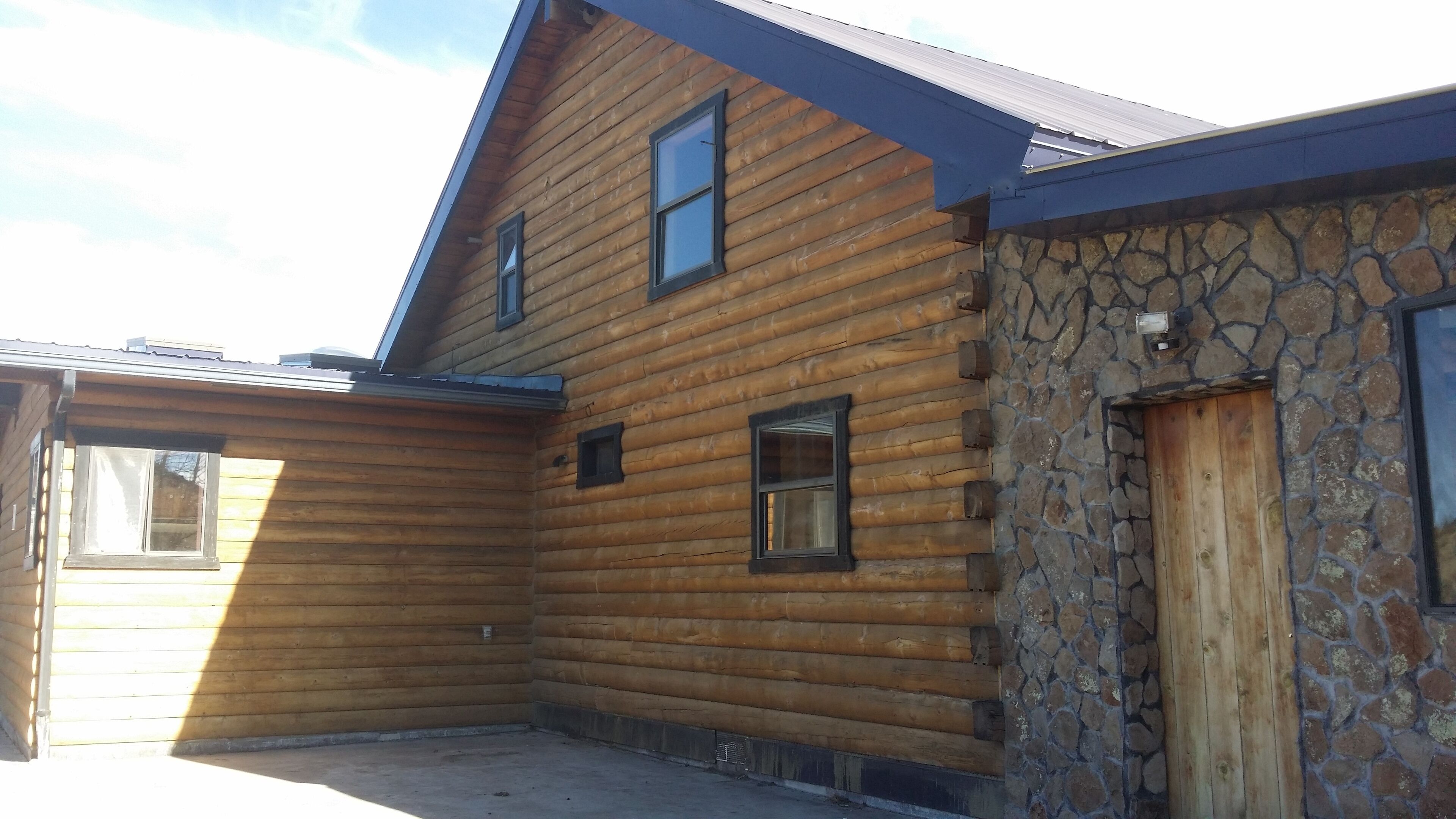 A wooden cabin with a stone exterior, a covered porch, and a door.