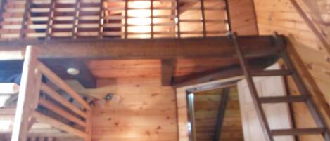 A wooden interior with a staircase leading to a loft area.