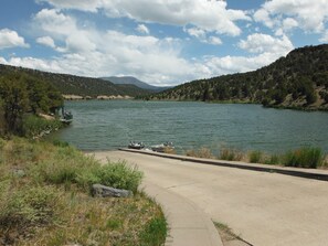 A concrete pathway leading to a body of water with boats docked, surrounded by hills and trees. - Fishing, Hunting, Hiking, And Lots Of Family Fun!! Direct View of Escudilla Mtn (Nutrioso)