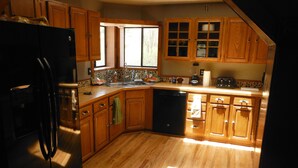 A kitchen with wooden cabinets, a dishwasher, and a refrigerator. - Fishing, Hunting, Hiking, And Lots Of Family Fun!! Direct View of Escudilla Mtn (Nutrioso)