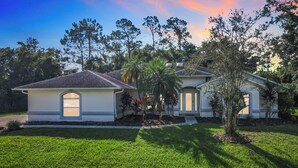 A residential house with a well-maintained lawn, a front porch, and a garage. - ALWAYS FREE POOL HEAT - 2 KINGS, Games room! 5 smart TV’s - S/Steel appliances (Kissimmee)