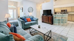 A spacious living area with a sofa set, a coffee table, and a television. - ALWAYS FREE POOL HEAT - 2 KINGS, Games room! 5 smart TV’s - S/Steel appliances (Kissimmee)