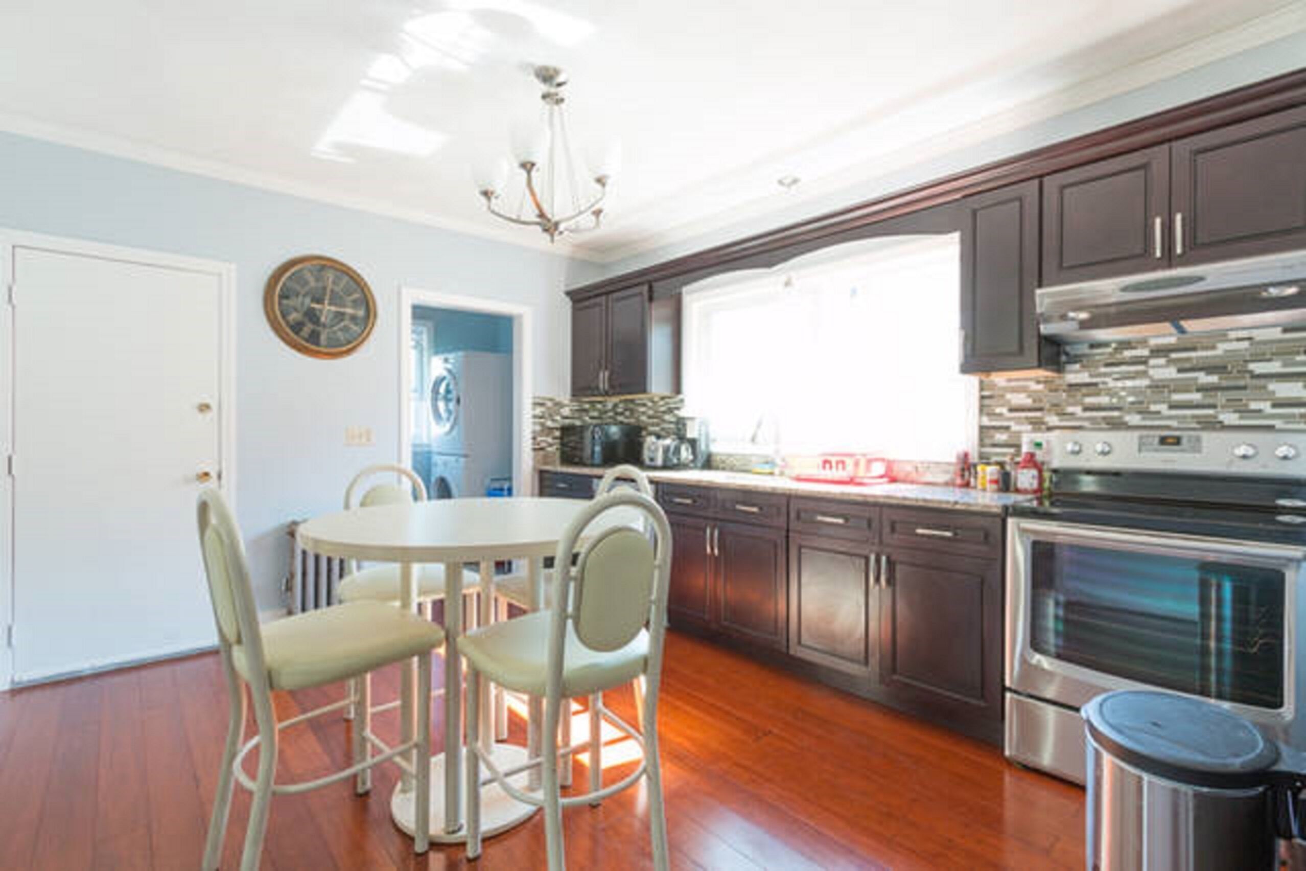 A modern kitchen with dark cabinets, stainless steel appliances, and a round dining table with chairs.
