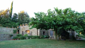 Un bâtiment en pierre doté d’un jardin, d’un espace extérieur aménagé pour s’asseoir et d’un arbre.