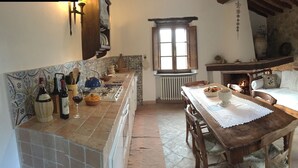 Une cuisine rustique avec une table en bois, une cheminée et un mur en pierre.