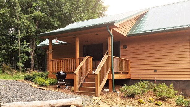 A wooden cabin with a porch, a barbecue grill, and a staircase leading to the entrance. - Blue Ridge Mountains (West Jefferson)