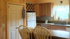 A kitchen with wooden cabinets, a refrigerator, a sink, and two chairs. - Blue Ridge Mountains (West Jefferson)