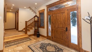 A wooden staircase with a clock, a wooden door with frosted glass panels, and a rug on the floor. - Last Nickel Lodge: Private Home on Golf Course, Hot Tub, Pool Table, Foosball (Breckenridge)
