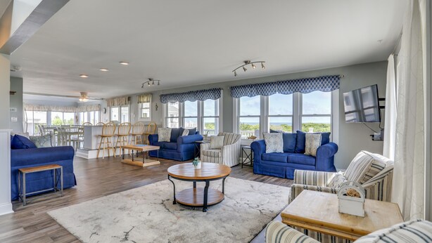 Un vaste espace de vie agrémenté de canapés bleus, d’une table basse ronde et d’une grande fenêtre offrant une vue panoramique.