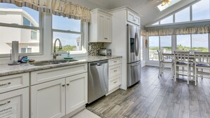 Une cuisine moderne avec des meubles blancs, des appareils en acier inoxydable et un grand îlot central.