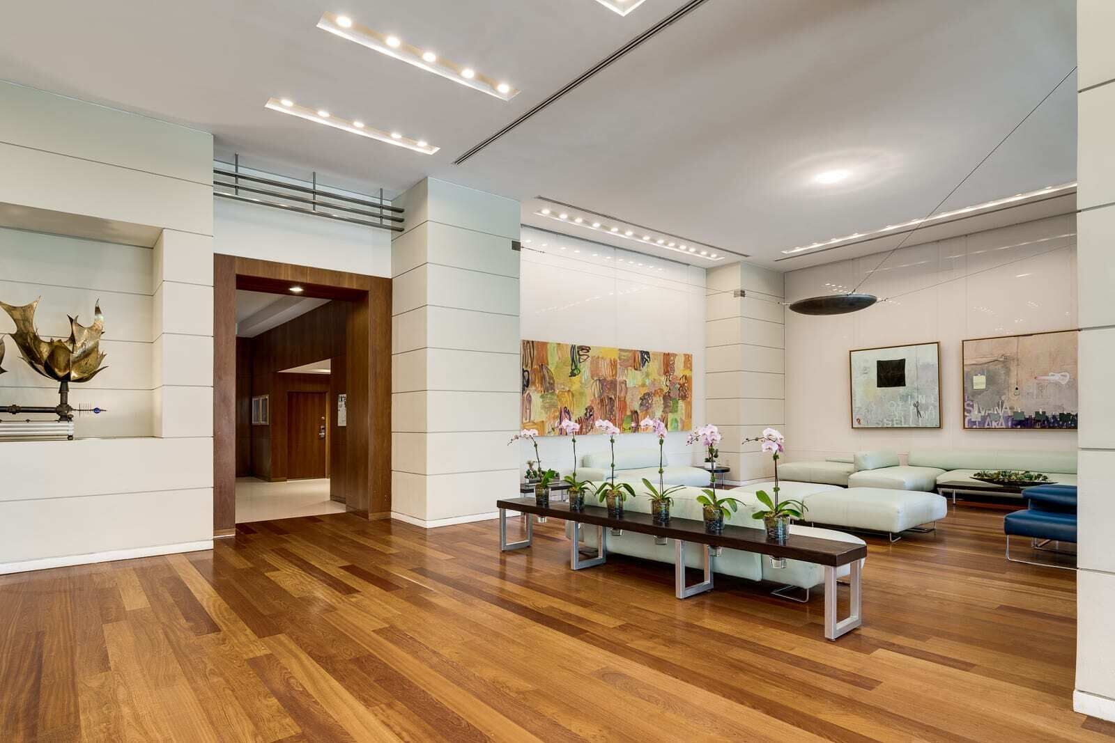 A spacious lobby with a wooden floor, a reception desk, a seating area with sofas, and a large abstract painting on the wall. - City&Ocean View Balcony. Pool & Hottub. Fast Wi-Fi (Miami)