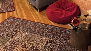 A cozy living room with a sofa, red bean bag, patterned rugs, and a fireplace. - Find your vacation here, at Merrynook Cabin (Pinehurst)