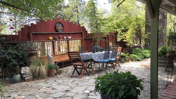A patio with stone flooring, wooden furniture, and potted plants. - Find your vacation here, at Merrynook Cabin (Pinehurst)