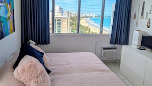 A bedroom with a large window, a bed, a dresser, and a wall-mounted air conditioner. - Rooftop, private garden penthouse, 2 beach view Bedrooms, free parking, WIFI (Isla Verde, Carolina)
