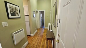 A hallway with a radiator, a framed picture, and a door with a gold doorknob.