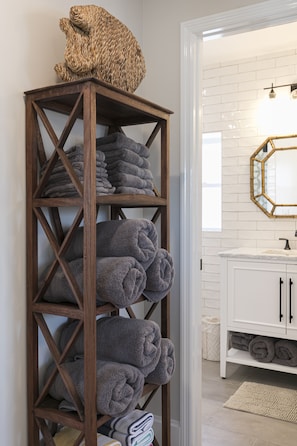 A wooden towel rack with folded towels, a white bathroom vanity, and a hexagonal mirror. - Upstairs so Sunny and Bright 2 Blocks to the Beach (Folly Beach)