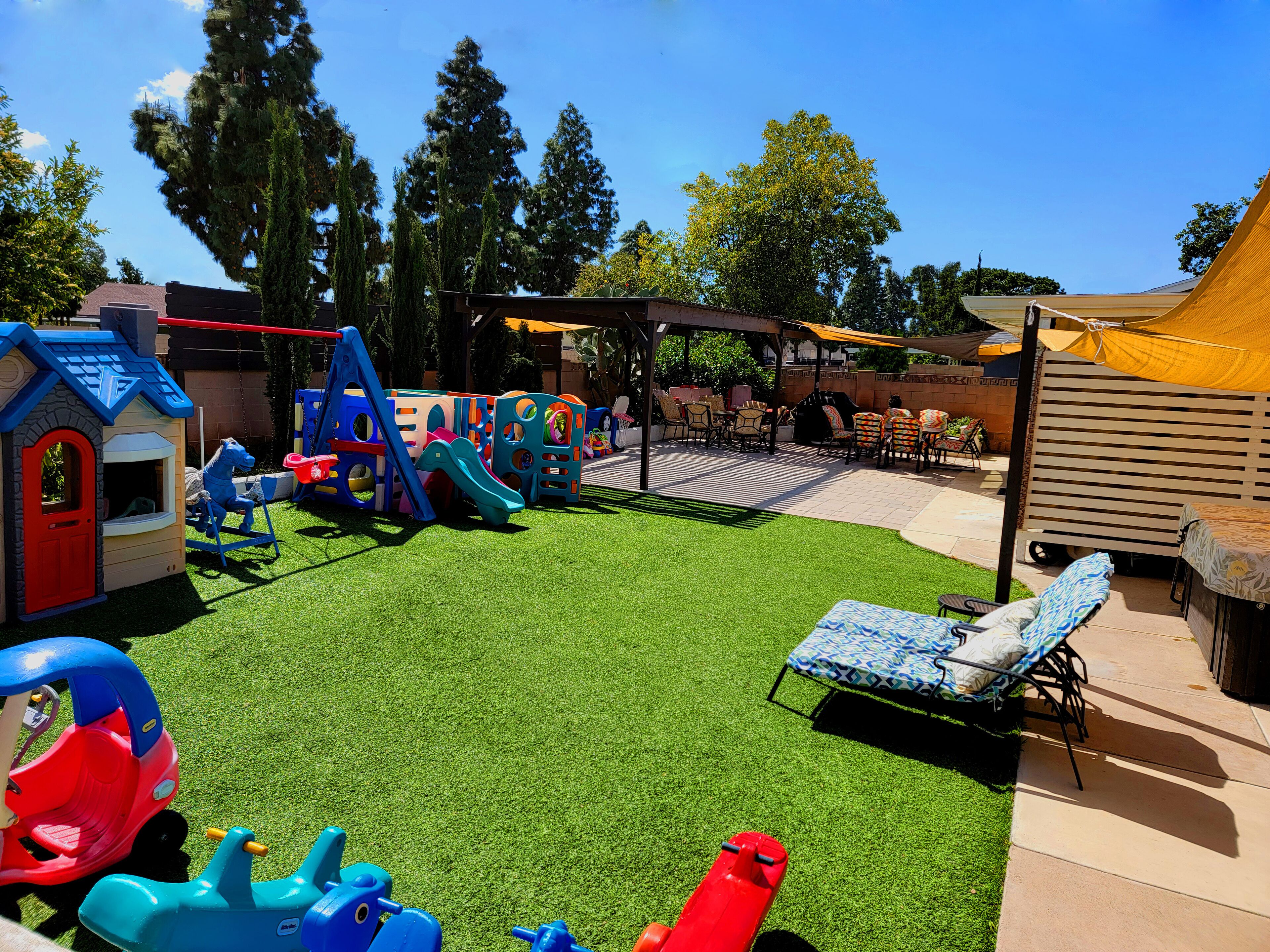 A children's play area with a slide, climbing structures, and a small house.