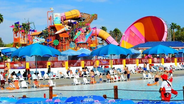 Een waterpark met verschillende glijbanen en een zwembadgedeelte met ligbedden.