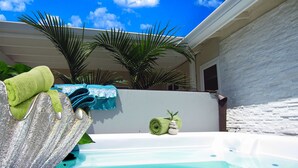 Een wellnessruimte met een bubbelbad, handdoeken en een palmboom.