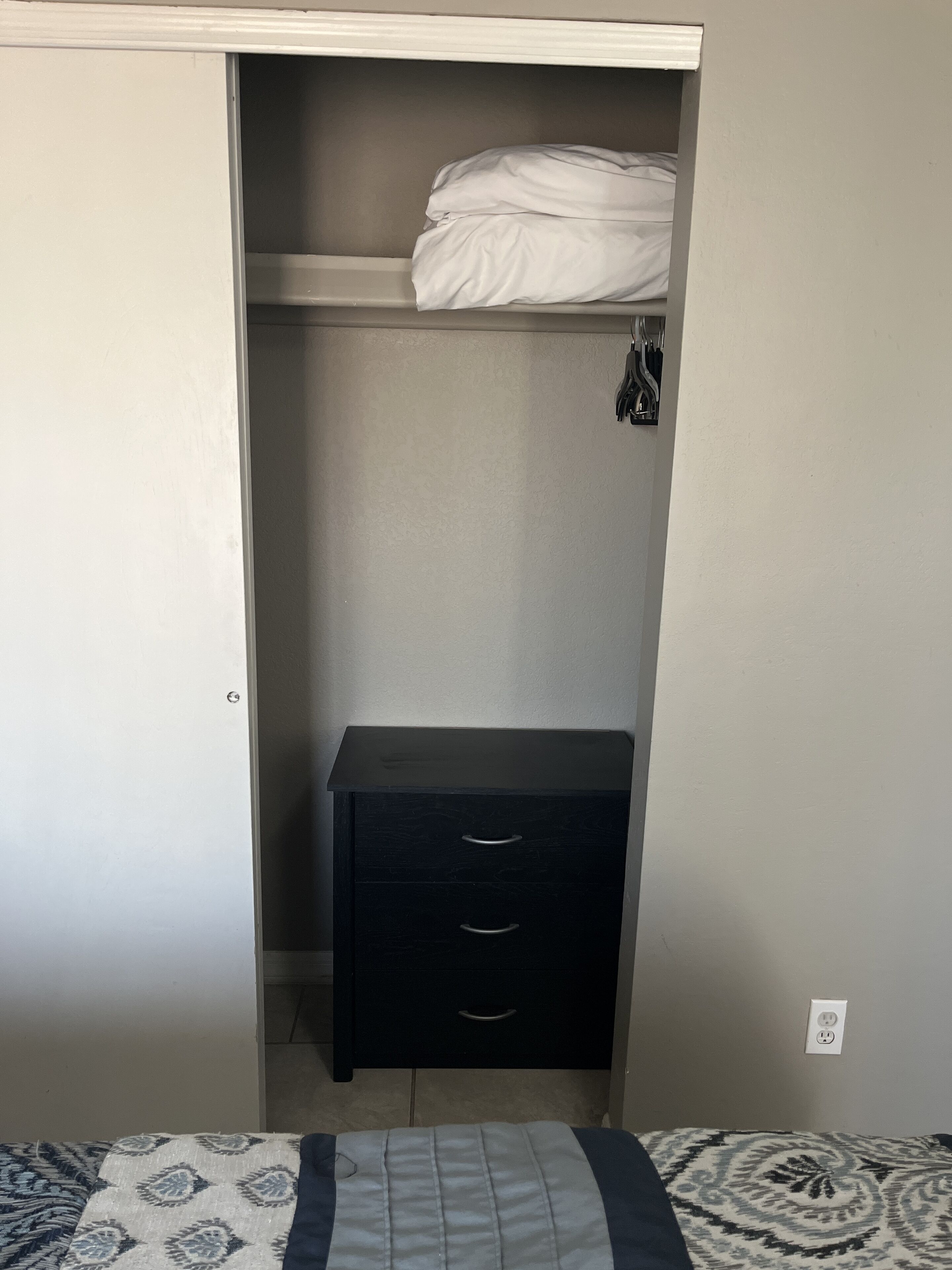 A bedroom with a bed, a bedside table, and a wardrobe.