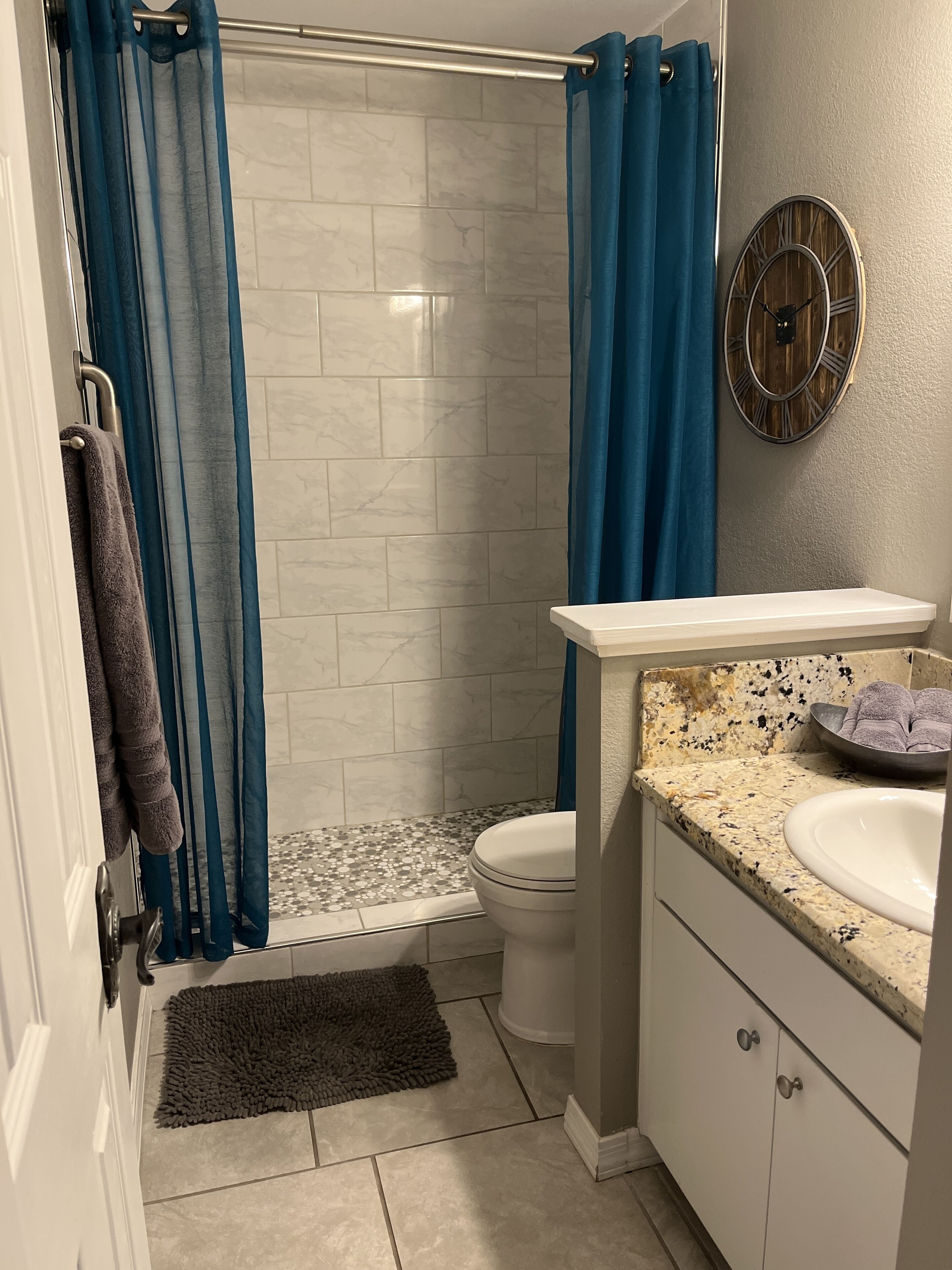 A bathroom with a shower, toilet, and vanity.