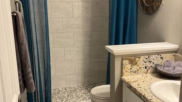 A bathroom with a shower, toilet, and vanity.