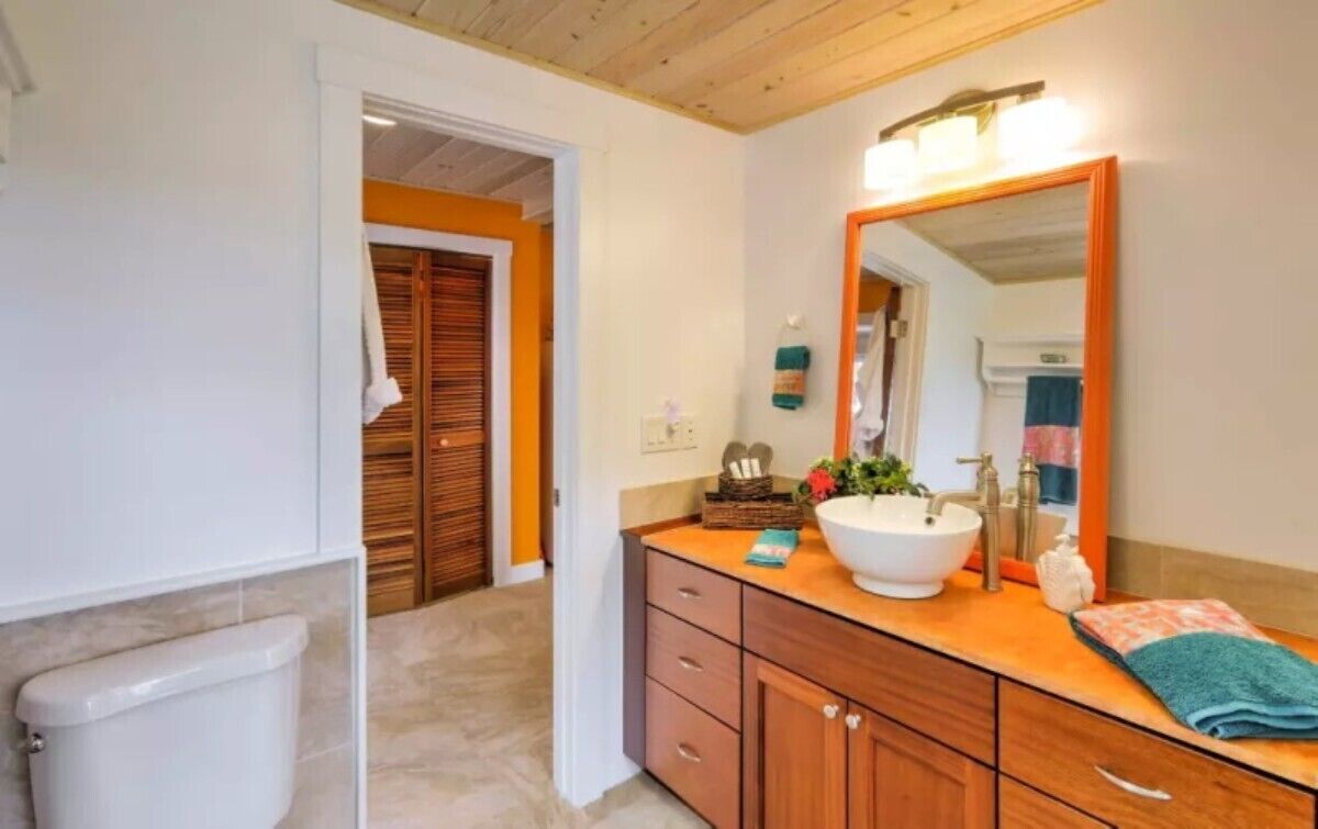 A bathroom with a wooden vanity, a white sink, and a large mirror.