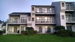 A multi-story residential building with balconies, large windows, and a well-maintained lawn. - Make memories on Grand Traverse East Bay. (Williamsburg)
