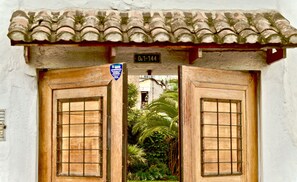 Enter a serene garden through this traditional door, framed by a white wall and tiled roof.