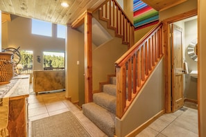 A wooden staircase with carpeted steps leading to a second floor. A rustic wooden table with a woven basket is visible in the foreground.