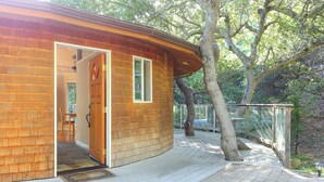 A wooden cabin with a curved roof, a door, and a window.