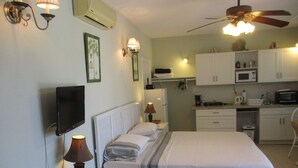 A bedroom with a bed, bedside lamps, a TV, and a small table with magazines. - EXCLUSIVE PROPERTY BEACHFRONT CONDO 3bed/3Bath DIRECTLY on beautiful HOOPERS BAY (Georgetown)