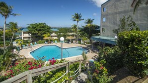 A pool area with lounge chairs, palm trees, and a view of the ocean. - Paradise @ Sapphire Village Studio- H-S WIFI -No Excess Owner Fees #307 (St Thomas)