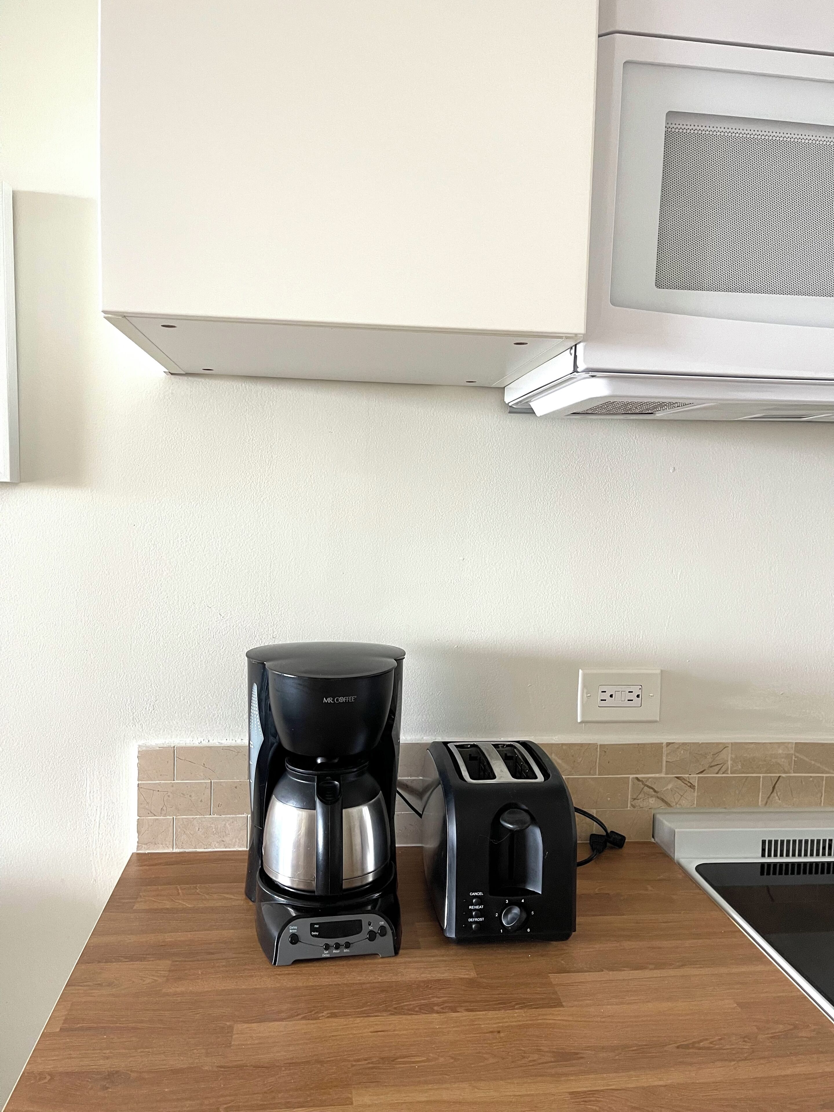 Una cocina equipada con cafetera, tostadora y microondas.